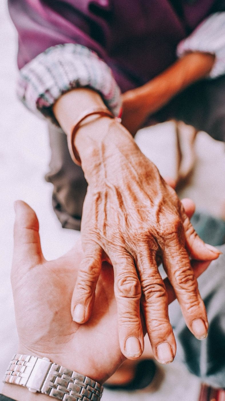 A caregiver gently holding an older person's hand